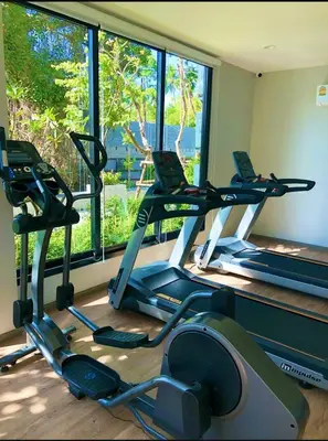 a gym with three treadmills in front of a window at naiyang beach in Phuket
