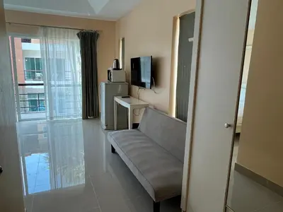 a living room with a couch and a television at Kata beach at pool house in Kata Beach