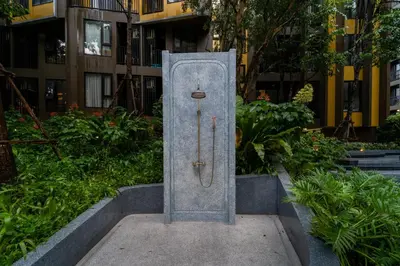 a metal door in the middle of a garden at 1BR Designer Mountain View Condo - Central Phuket in Phuket Town