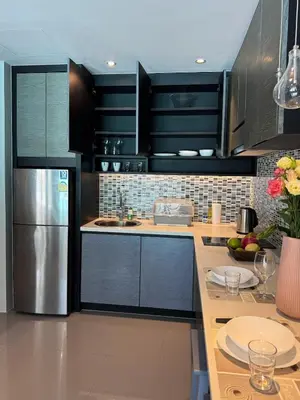 a kitchen with black cabinets and a stainless steel refrigerator at Kamala City Gate 1 Bdr Pool View in Kamala Beach