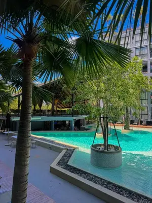 a swimming pool with two palm trees and a building at Kamala City Gate 1 Bdr Pool View in Kamala Beach