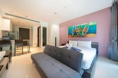 a bedroom with a bed and a couch and a kitchen at Private apartment at Emerald Terrace by Lofty in Patong Beach