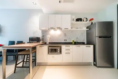 a kitchen with white cabinets and a stainless steel refrigerator at Private apartment at Emerald Terrace by Lofty in Patong Beach