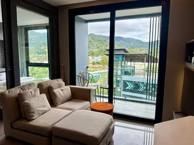 a living room with a couch and a large window at Room in Kamala at Citygate Condo in Kamala Beach