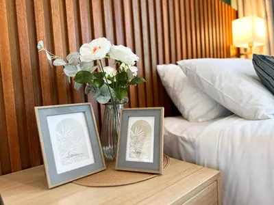 two picture frames on a table with a vase of flowers at La Nissta Villa 4bdr pool Villa Phuket in Koh Lone
