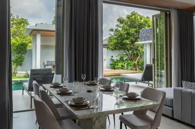 a dining room with a table and chairs and a large window at Botanica Foresta x MonthStayZ Thailand in Bang Tao Beach