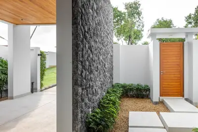 a house with a wooden door next to a tree at Botanica Foresta x MonthStayZ Thailand in Bang Tao Beach