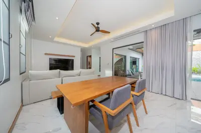 a dining room and living room with a wooden table and chairs at Nicky Villa Luxury Private Haven in BangTao Laguna in Laguna Phuket