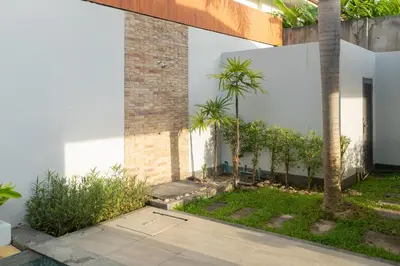a courtyard with palm trees next to a building at Nicky Villa Luxury Private Haven in BangTao Laguna in Laguna Phuket