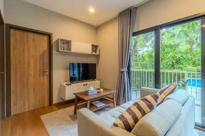 a living room with a couch and a large window at C241 2BR Pool Access 5 Min Walk to Rawai Beach in Rawai Beach