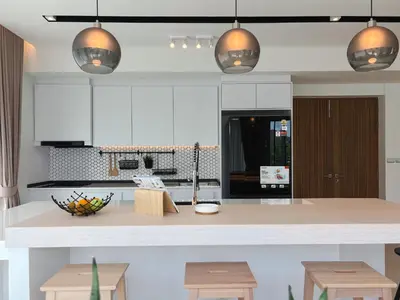 a kitchen with white cabinets and a island with wooden stools at The Eden Hill in Phuket Town
