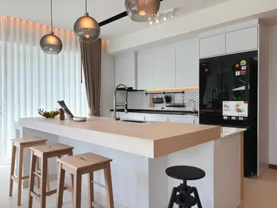 a kitchen with white cabinets and a counter with stools at The Eden Hill in Phuket Town
