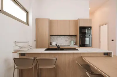 a kitchen with a sink and a counter with chairs at Вилла в поселке БанБуа in Rawai Beach