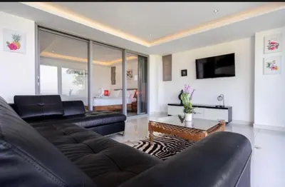 a living room with a black couch and a tv at Luxury Penthouse with Private Pool at View Phuket F9 in Karon Beach