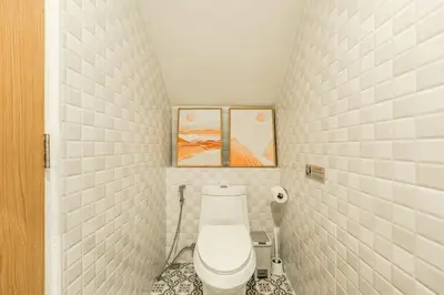 a bathroom with a toilet and two paintings on the wall at Nai Harn Beach Holiday Home - Rawai 4bdr in Rawai Beach