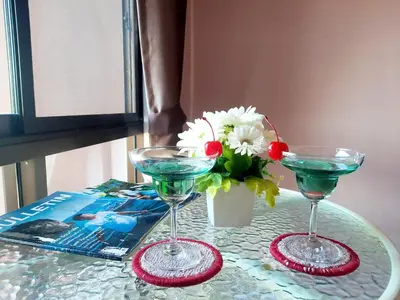 two martini glasses on a table with a vase of flowers at Purimas Resortel in Rawai Beach
