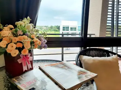 a table with a vase of flowers and a book at Purimas Resortel in Rawai Beach