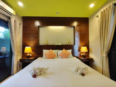 a bedroom with a large white bed with two towels at Purimas Resortel in Rawai Beach