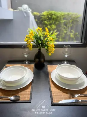 a table with white plates and a vase with yellow flowers at Condo for rent chalong rawai 106 in Ban Klang