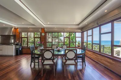 a dining room with a table and chairs and windows at 35 - Vast Beach Front Villa in Kamala Beach