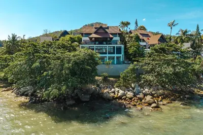 a house sitting on top of a rocky island in the water at 35 - Vast Beach Front Villa in Kamala Beach