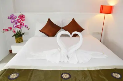 two white swans making a heart on a bed at Angelina Guesthouse in Patong Beach