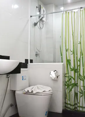 a white bathroom with a toilet and a shower at Angelina Guesthouse in Patong Beach