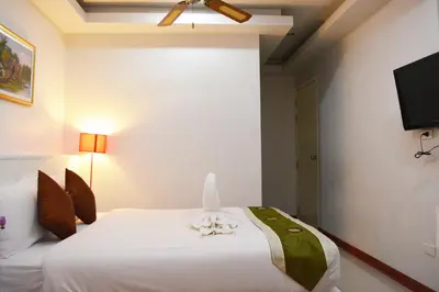 a bedroom with a white bed and a flat screen tv at Angelina Guesthouse in Patong Beach