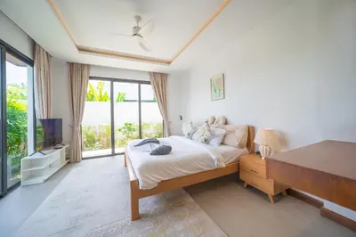 a bedroom with a bed and a desk and a television at BangTao Luxury 5 Bedroom 1200sqm Modern Bali Style Holiday Villa Quiet and Private Large Private Pool Large Garden in Bang Tao Beach
