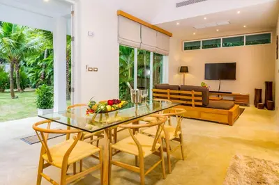 a dining room and living room with a glass table and chairs at Baan Klong III in Ko Yao Noi