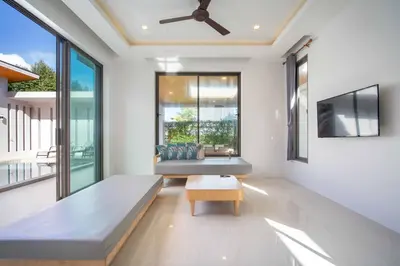 a living room with a couch and a tv at Elm pool villa Phuket in Kata Beach