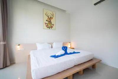 a bedroom with a white bed with blue shoes on it at Elm pool villa Phuket in Kata Beach