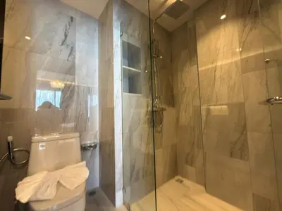 a bathroom with a shower and a toilet and a glass door at Новая студия Bellevue Bangtao in Laguna Phuket
