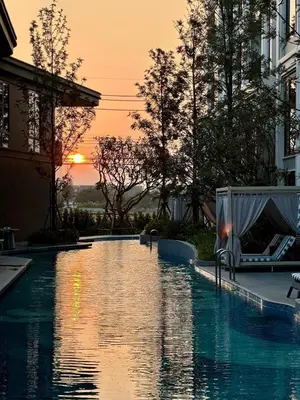 a swimming pool with the sunset in the background at Новая студия Bellevue Bangtao in Laguna Phuket
