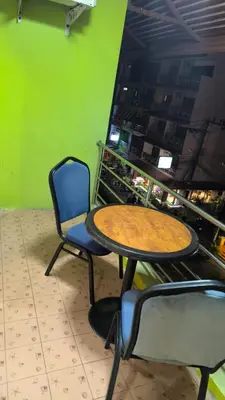 a table and chairs in a room with a green wall at Didim Guest House Patong in Patong Beach