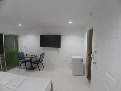 a white room with a table and a tv on a wall at Didim Guest House Patong in Patong Beach