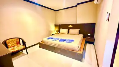 a small bedroom with a bed and a chair at Hotel Hollywood Inn Love Patong in Patong Beach