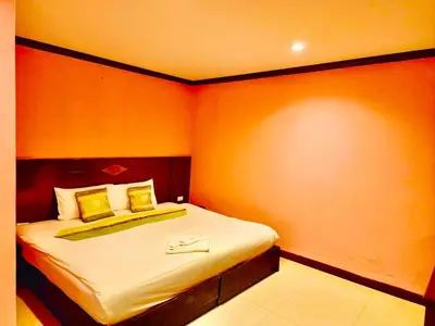 a small bedroom with a bed with orange walls at Hotel Hollywood Inn Love Patong in Patong Beach