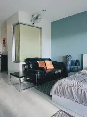 a living room with a black leather couch and a bed at CHIC Beautiful apartment by the seaside, terrace, pool, free gym in Karon Beach