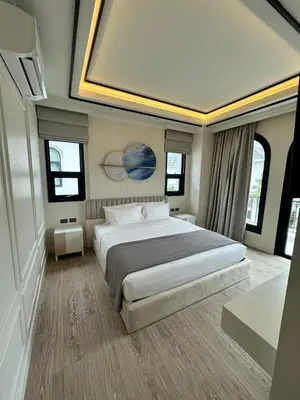 a bedroom with a large bed in a room with windows at Fifth Element Pool Villa By Ere in Laguna Phuket