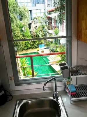 a kitchen sink with a view of a pool through a window at Relife apartments Большая квартира с панорамным видом на горы на Най Харне in Phuket Town