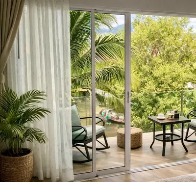 a room with a sliding glass door with a chair and a table at The Escape Kamala in Kamala Beach