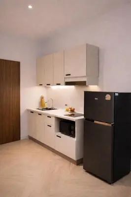 a kitchen with white cabinets and a black refrigerator at The Escape Kamala in Kamala Beach