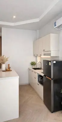 a kitchen with a black refrigerator and white cabinets at The Escape Kamala in Kamala Beach