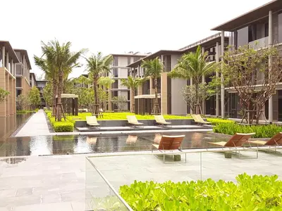 a resort with a pool and chairs and palm trees at Baan Mai Khao Beach Residence in Mai Khao Beach
