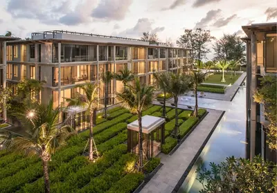 an exterior view of a building with a pool and palm trees at Baan Mai Khao Beach Residence in Mai Khao Beach