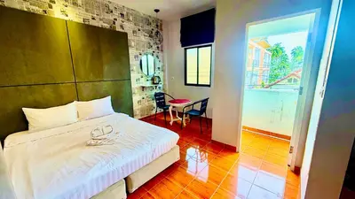 a bedroom with a bed and a table and a room at Cozy Bay Rawai in Phuket Town