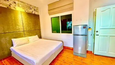 a small bedroom with a bed and a refrigerator at Cozy Bay Rawai in Phuket Town