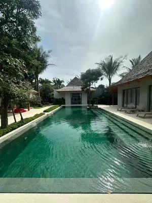 a swimming pool in front of a house at Anchan Tropicana By Ere in Ban Phru Champa