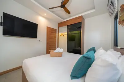 a bedroom with a white bed with a flat screen tv at Nicky Luxury Private Pool Villa in BangTao Laguna in Laguna Phuket
